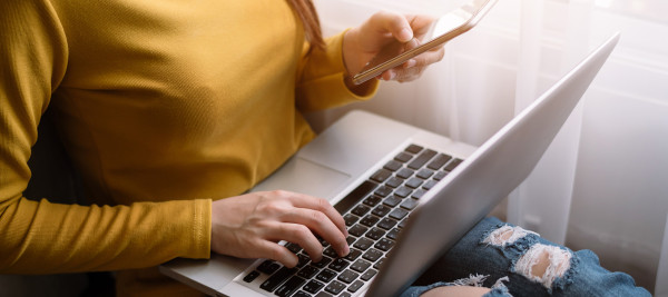 A person using a laptop and a phone to do a search.