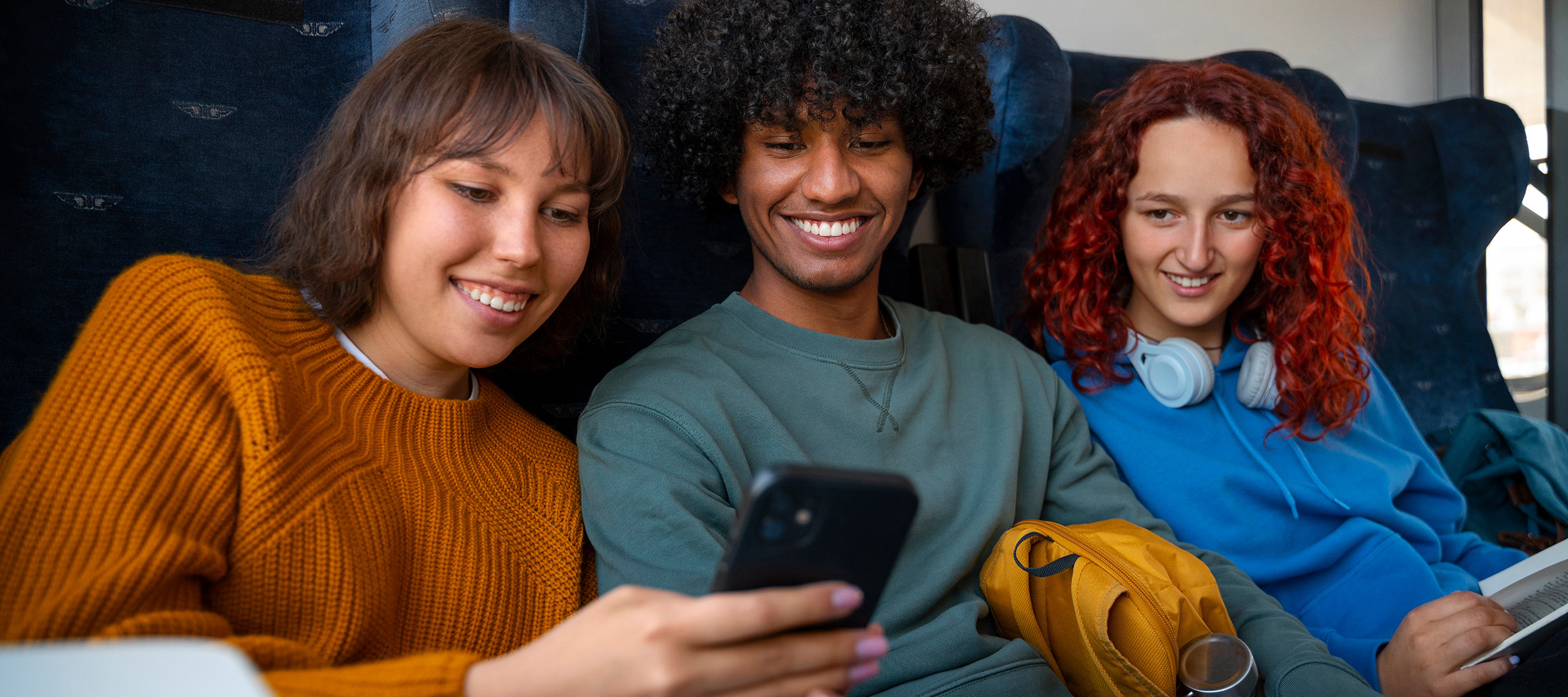 Friends huddled around a phone, looking at the screen.